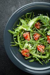 Fresh vegetable salad from organic vegetables in a plate on a black background.