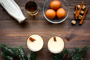 Ingredients for eggnog. Eggs, milk, cinnamon, whiskey on dark wooden background top view