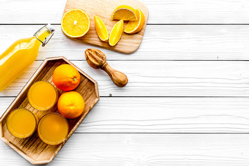 Make orange juice. Juicer, beverage in bottle and glasses near slices of oranges on white wooden background top view copyspace