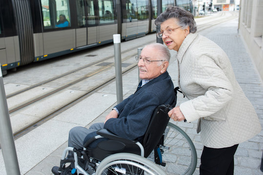 senior wife helping husband in wheelchair