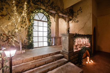Fototapeta na wymiar the scenery of the Studio or theater. Entrance in an old architecture with staircase and columns. Christmas decoration with garlands and fir branches