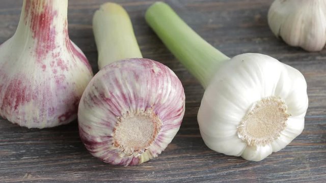 Fresh garlic bulbs on wooden table. Closeup. Slow pan.