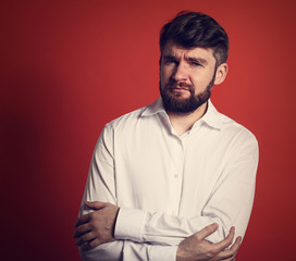 Thinking serious bearded charismatic man in whirt shirt looking on orange background with empty copy space. Closeup toned portrait