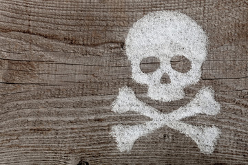 Filled by flour Skull and bones on old wood plank as background 