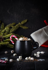 Obraz na płótnie Canvas black mug with marshmallow and candy on wooden background