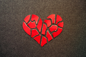 Paper red broken heart on dark felt background. Mosaic paper heart from pieces. Cracked heart...