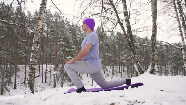 man practicing yoga in nature in winter