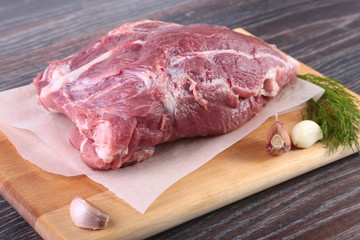Raw pork steaks on wooden board with herbs, garlic and spices ready for cooking. Selective focus.