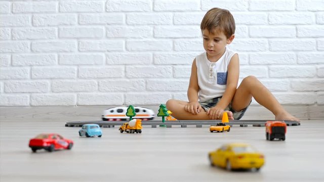 Low angle Little caucasian boy playing with cars and train on the floor, 4k