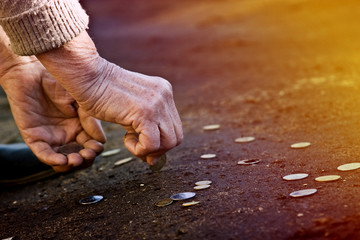 Old grandmother collects coins along the road