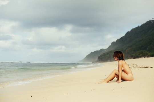 Beautiful woman without swimming suite on ocean shore. Nudist beach