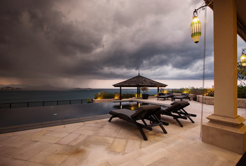Storm coming up and dark clouds above Swimming pool with sea view in luxury villa, weather and...