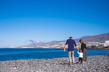 mom, dad and baby are walking on the beach of Tenerife