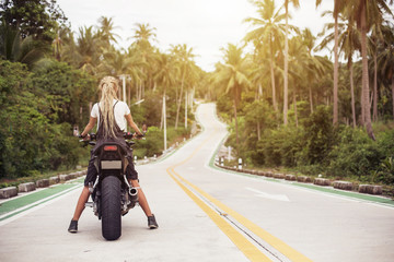 Fototapeta premium Portrait of female Biker sitting on big motorcycle. Girl driver with dread locks, travel way concept