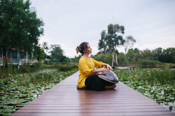Woman playing on hang drum outdoor on beautiful lake