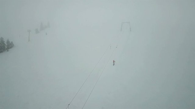 Snowboarder climbs to the top of the mountain with a lift