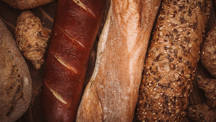 Many mixed baked breads and rolls on rustic wooden table