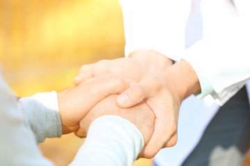 Young caregiver holding hands with senior man, closeup