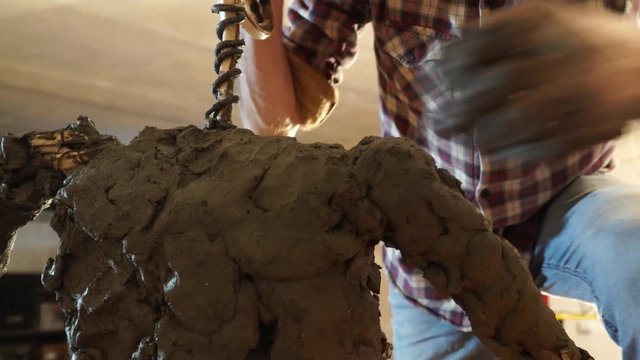 the sculptor is working on the creation of a monument - the process of making a monument in full growth from clay – 4k video