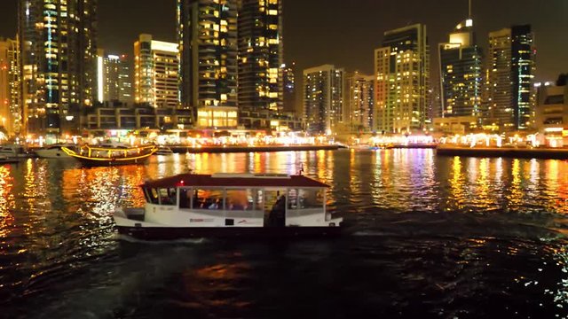 The night illumination of Dubai Marina and Dhow boat in Dubai, UAE. It is an artificial canal city. Motor boat, beautiful night city landscape background