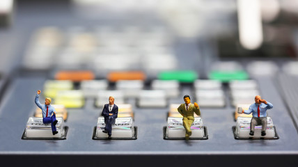 Miniature people : businessman sitting on switcher control of Television Broadcast,color buttons