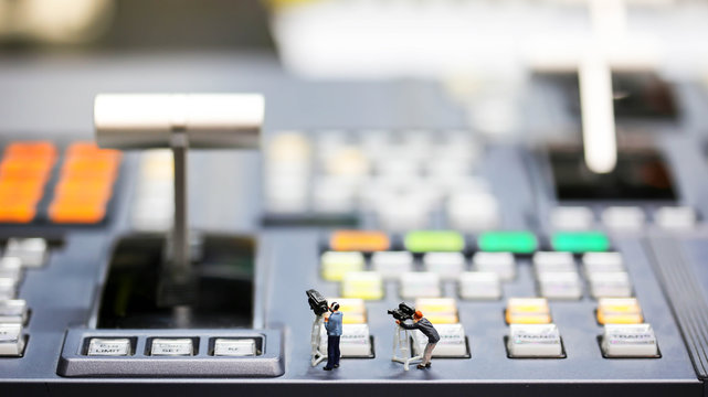 Miniature people : journalists , cameraman ,Videographer at work shooting on switcher control of Television Broadcast,color buttons
