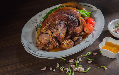Stewed pork leg in white dish on wooden background with dim light Asia food / Still Life and Selective focus..