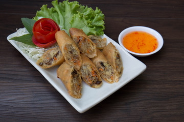 Fried Veg. Spring rolls on white dish with sweet sauce on wooden table / Selective focus image*