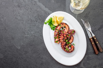 Fototapeta na wymiar Grilled octopus on white plate serverd with white wine , top view. Seafood