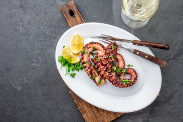 Grilled octopus on white plate serverd with white wine , top view. Seafood © lblinova
