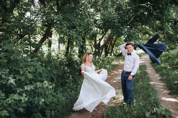 The newlyweds joke and laugh. The bride is dancing with a dress in her hands, the groom is waving a jacket. Wedding joke.