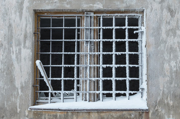 The wall of concrete and the window closed with iron bars.