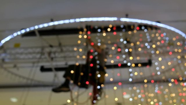 Industrial climber mounts Christmas decorations in the unsupported space in the shopping center