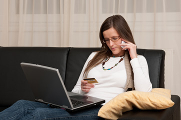 Attractive young woman shopping online with laptop and credit card