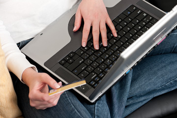 Attractive young woman shopping online with laptop and credit card