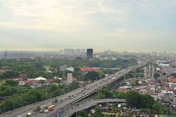 Cityscape of Jakarta city with buildings, houses, and busy road.