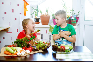 Fun children prepare salad vegetables . Happy kids in the kitchen . The concept of a healthy vegetarian diet