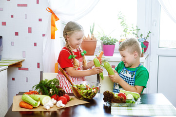 Fun children prepare salad vegetables . Happy kids in the kitchen . The concept of a healthy vegetarian diet