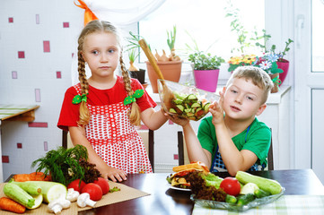 Fun children prepare salad vegetables . Happy kids in the kitchen . The concept of a healthy...