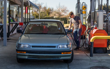 Young man fueling his car at gas station