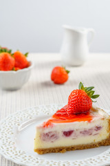 Delicious cheesecake with strawberry on a table against white wall.