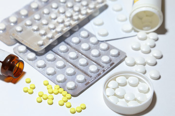 Various tablets - analgesics, antidepressants, vitamins, antiviral drugs scattered on a white background.