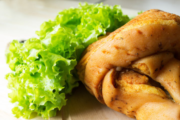 Smoked pork knuckle with green salad. A traditional German snack for beer. Selective focus.