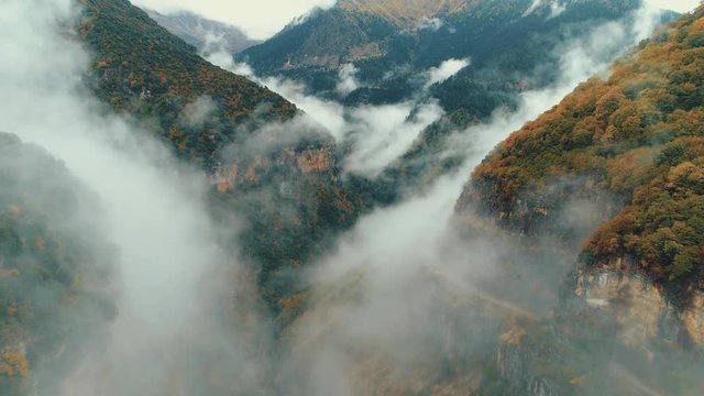 Aerial pass inside a deep gorge/canyon of a national park in Greece during autumn/winter while fog slowly kicks in. 