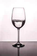 Wineglass with pouring water on a white background and glass