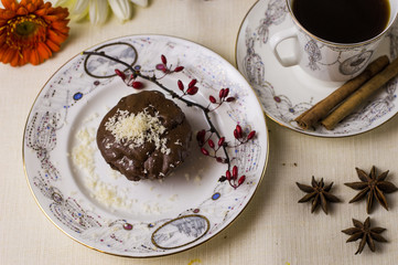 Chocolate fondant on a white plate with coffee and flowers