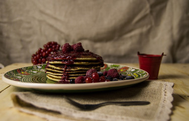 A pancake on the Christmas table with tea and raspberry jam