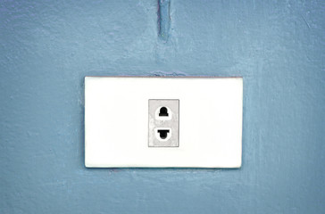 Electric plug socket on blue pastel wall.