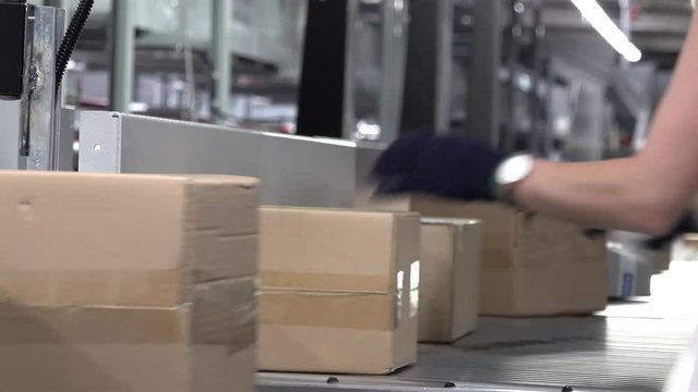 Lady correcting parcels on conveyor - time lapse