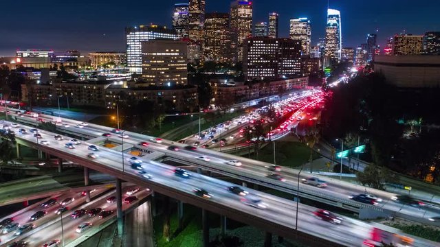 Cinematic urban aerial time lapse of downtown Los Angeles freeway traffic with the stunning city skyline and skyscrapers at twilight.
